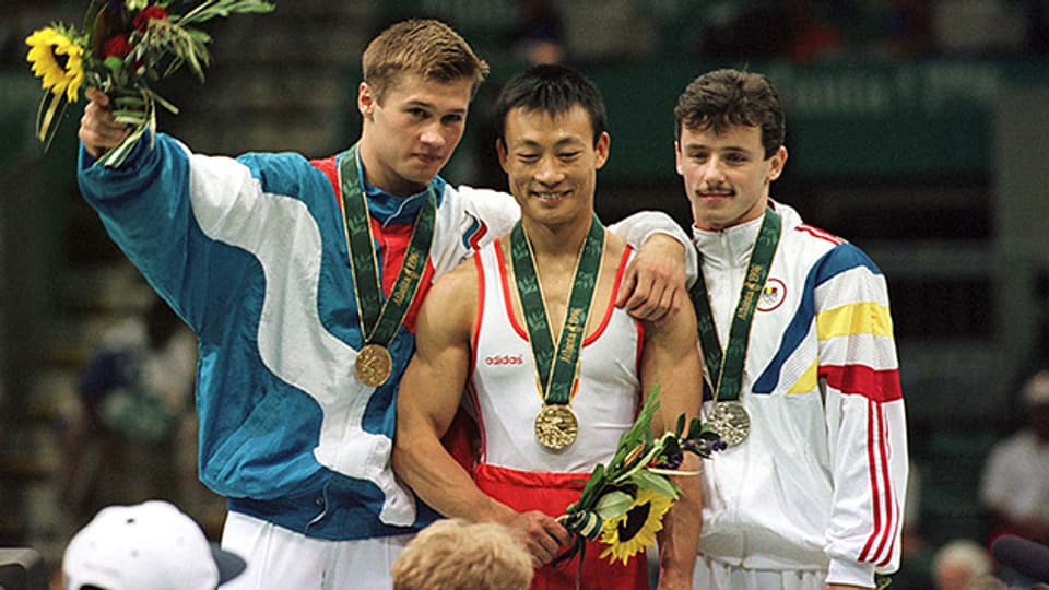 Der Schweizer Olympiasieger Donghua Li mit Alexei Nemov (links) und Marius Urzica nach der Siegerehrung.