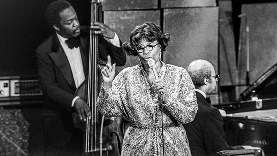 Die amerikanische Jazzsängerin Ella Fitzgerald (1917-1996) im Juli 1975 zusammen mit Keter Betts (Bass) und Tommy Flanagan (Klavier) am Montreux Jazz Festival.