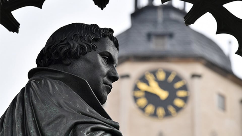 Denkmal von Reformator Martin Luther (1483-1546) neben dem Turm der Stadtkirche auf dem Markt in Wittenberg.