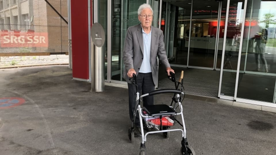 David Künzler ist pensionierter Hausarzt und gondelt mit seinem Rollator durch die Schweiz. Hier ist er vor den SRF-Studio im Leutschenbach, Zürich.