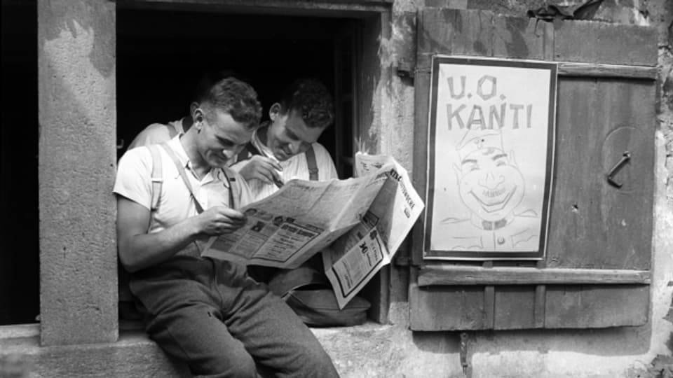 Soldaten der Schweizer Armee im Aktivdienst lesen vor der Unteroffizierskantine eine Zeitung, aufgenommen im Kriegsjahr 1939.