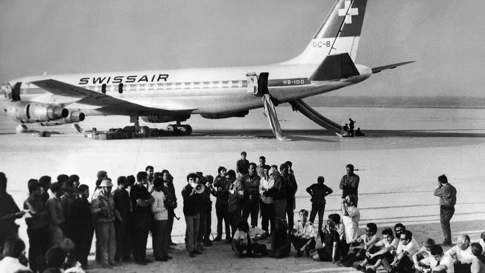 Umringt von Journalisten sitzen Passagiere und Flugpersonal der entführten Swissair-Maschine am 9. September 1970 auf dem Flugfeld «Dawson's Field» nahe Zarqa in Jordanien.