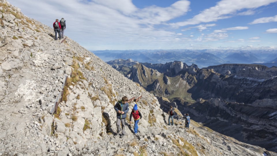 Bergwanderer steigenüber Grüenboehl im Alpstein dem Säntis entgegen, im Hintergrund der Hohe Kasten, Marwees, Hundstein und Roslenfirst.