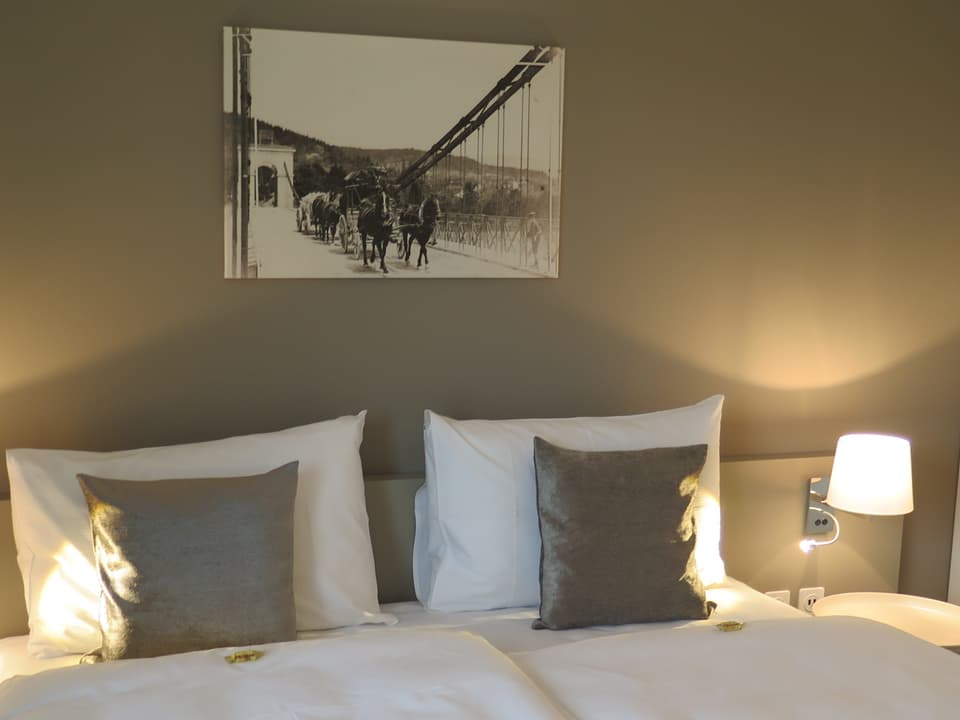 Hotelzimmer mit Bett, darüber hängt eine historische Fotografie