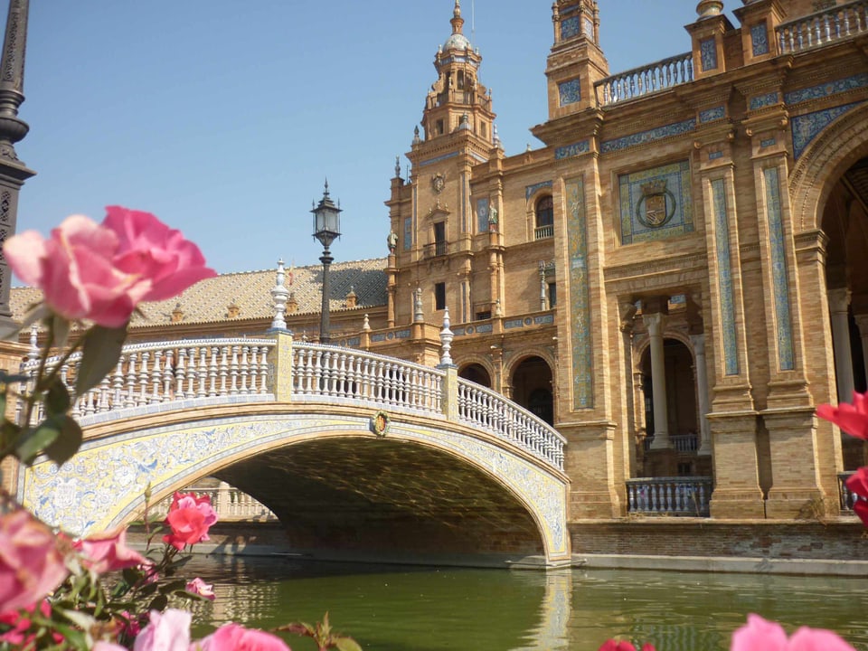 Fluss und Kirche mit rosa Rosen in Sevilla
