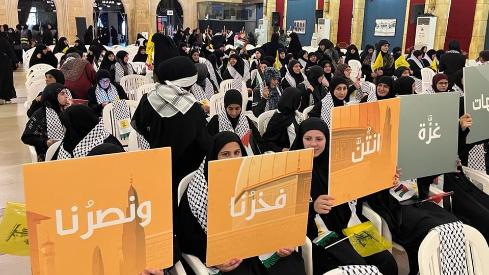 Frauen mit Hidschab halten arbisch beschriftete Tafeln hoch