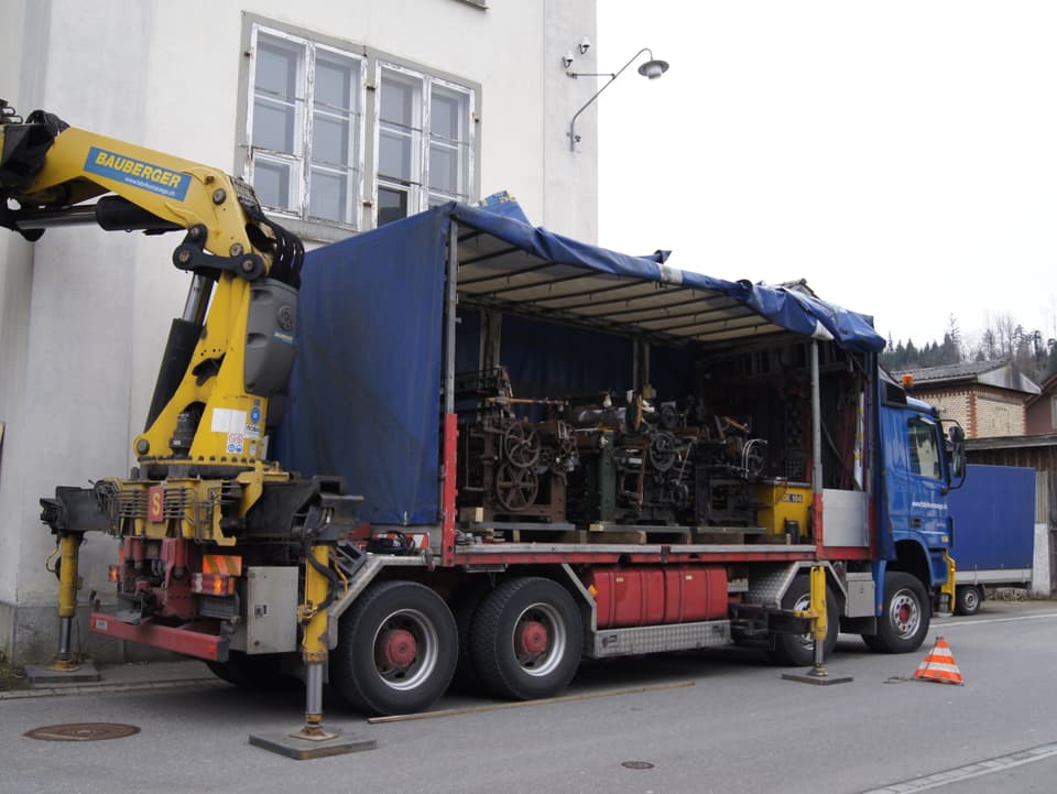 Lastwagen mit drei Webstühlen drin vor Fabrik
