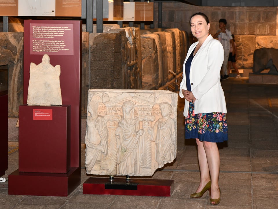 Frau posiert in einem Museum neben antiken Objekten
