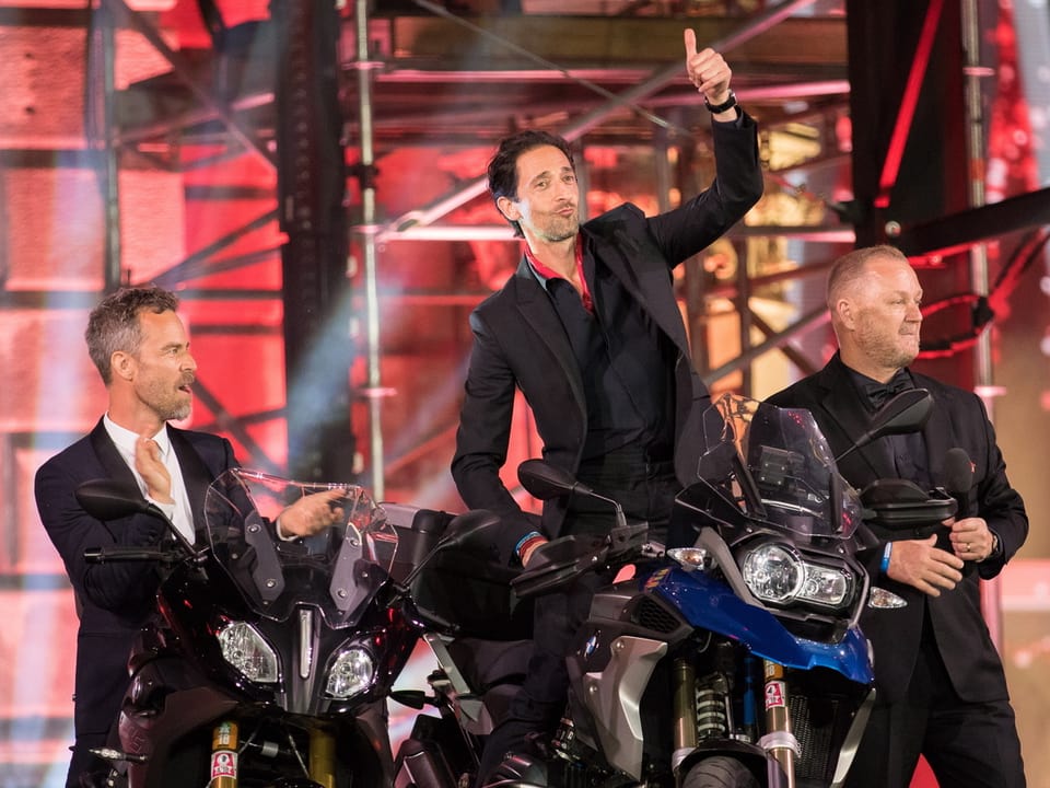Drei Männer mit zwei Motorrädern auf Bühne