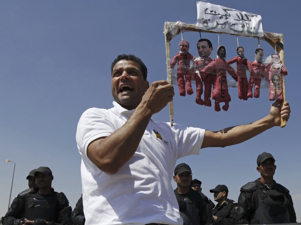 Mann hält Galgen in die Höhe an denen Mubarak, dessen Söhne und die anderen Angeklagten hängen.