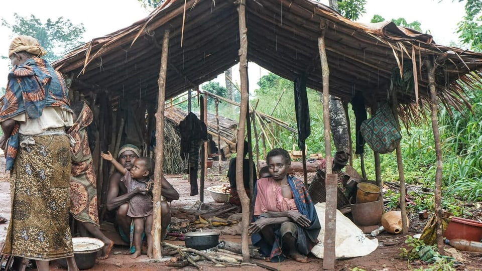 Aka-Frauen mit Kindern sitzen im Regen in einer Hütte