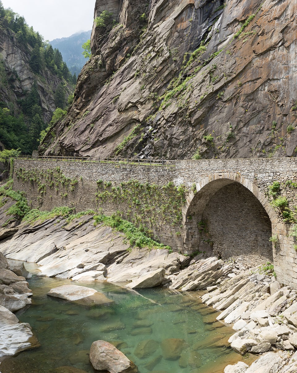 Eine Brücke an einem steilen Fels. 