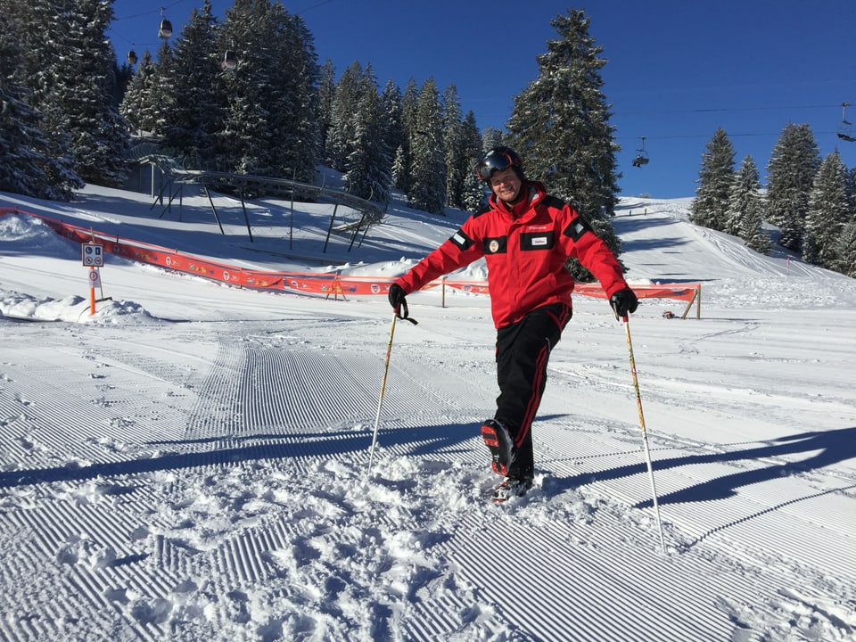 Skilehrer zeigt Aufwärmübung im Schnee.