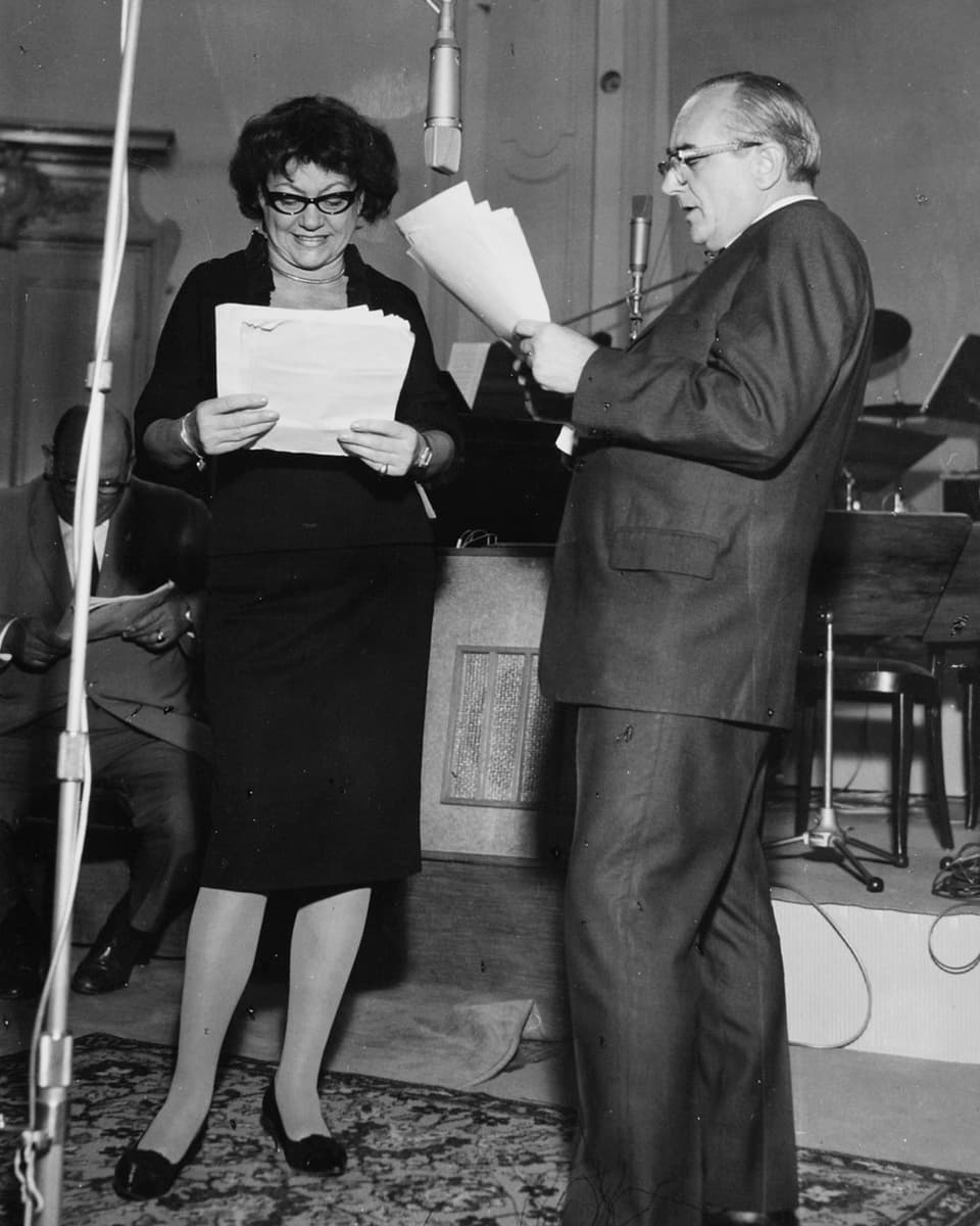 Margrit Rainer und Ruedi Walter stehen mit ihren Manuskripten vor einem Mikrofon im Aufnahmestudio.