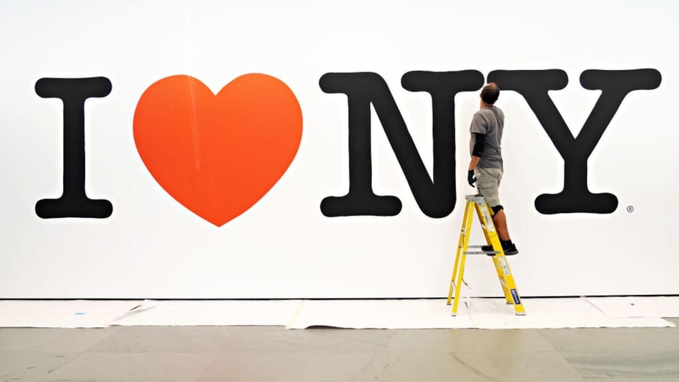 Ein Mann steht auf einer Leiter und legt Hand an den überlebensgrossen Schriftzug «I Love NY» an einer Wand