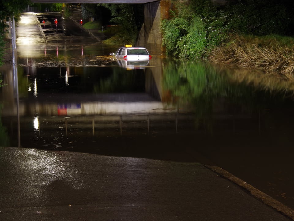 Ein Taxi geht auf einer überschwemmten Strasse in Chur baden. (Stadtpolizei Chur)