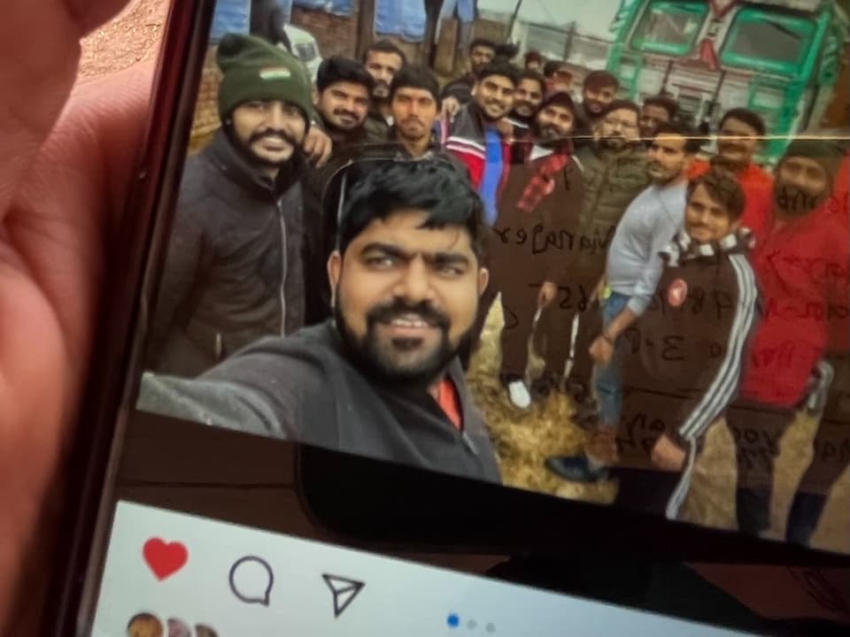 Handydisplay zeigt Selfie von Gruppe lächelnder Männer.