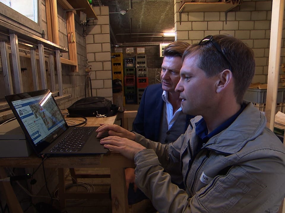Zwei Männer schauen in einen Laptop.