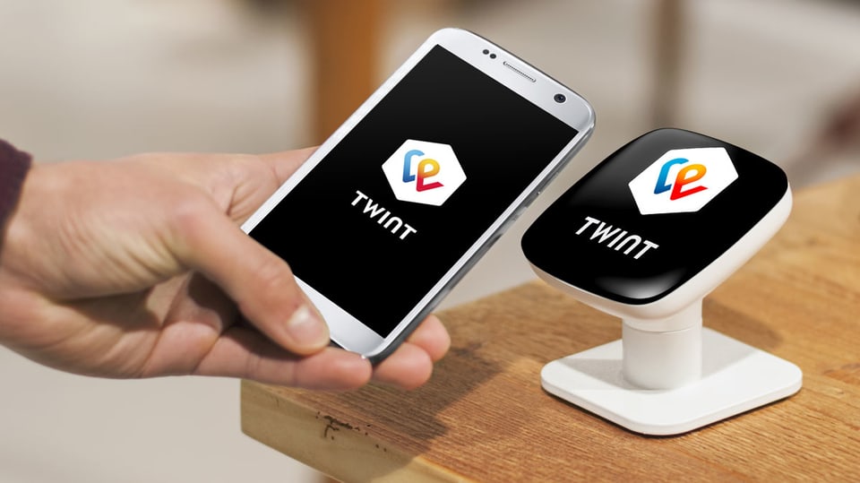 Jemand hält ein Smartphone mit Twint-App an einen Twint-Beacon.