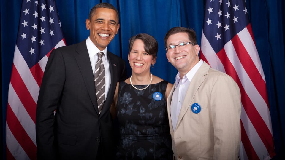 Suzi LeVine posiert mit ihrem Gatten und Barack Obama vor zwei US-Flaggen in Washington.