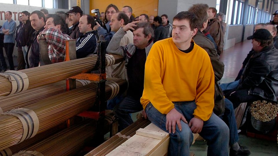 Arbeiter sind in einer Fabrikhalle zu einer Orientierung versammelt.
