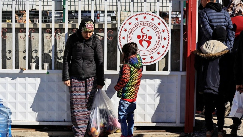 Eine Frau und ein Kind stehen vor einem Zentrum für Erdbebenopfer