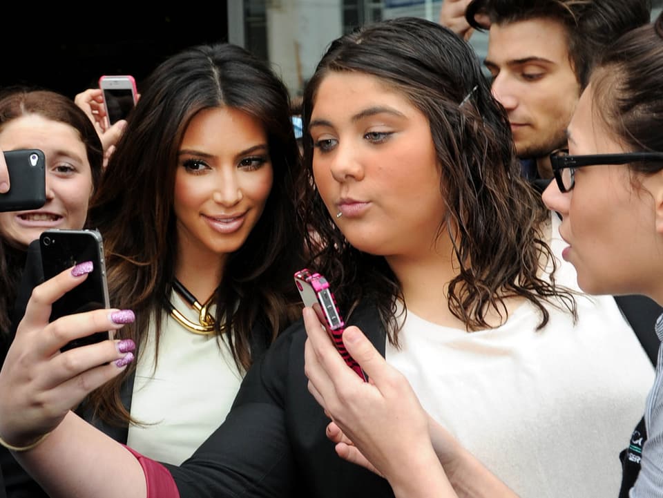 Kim Kardashian posiert mit einem Fan.