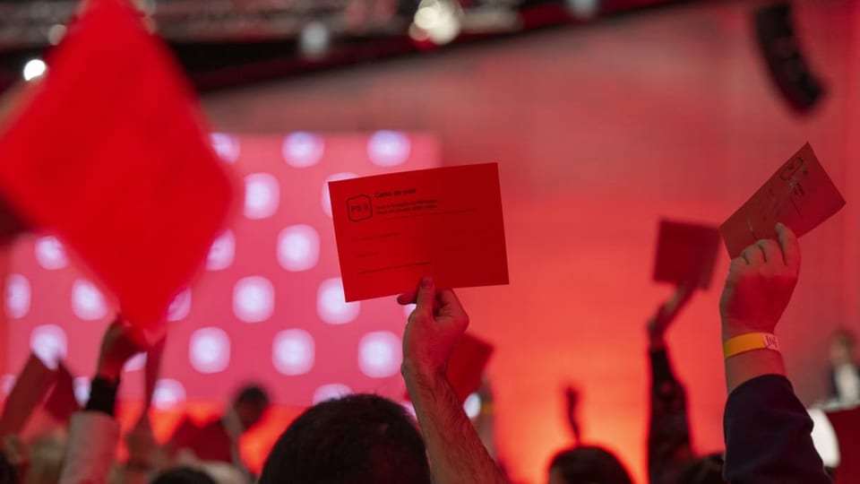 Abstimmung am SP-Parteitag – Teilnehmerinnen und Teilnehmer strecken Abstimmungskarten in die Höhe, alles in rotem Licht