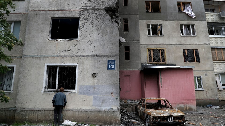 Ein Anwohner inspiziert eine Wohnung in einem beschossenen Wohngebiet in der Ukraine.