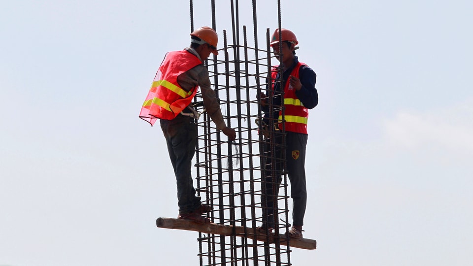 Zwei Bauarbeiter arbeiten an einem Eisengerüst.