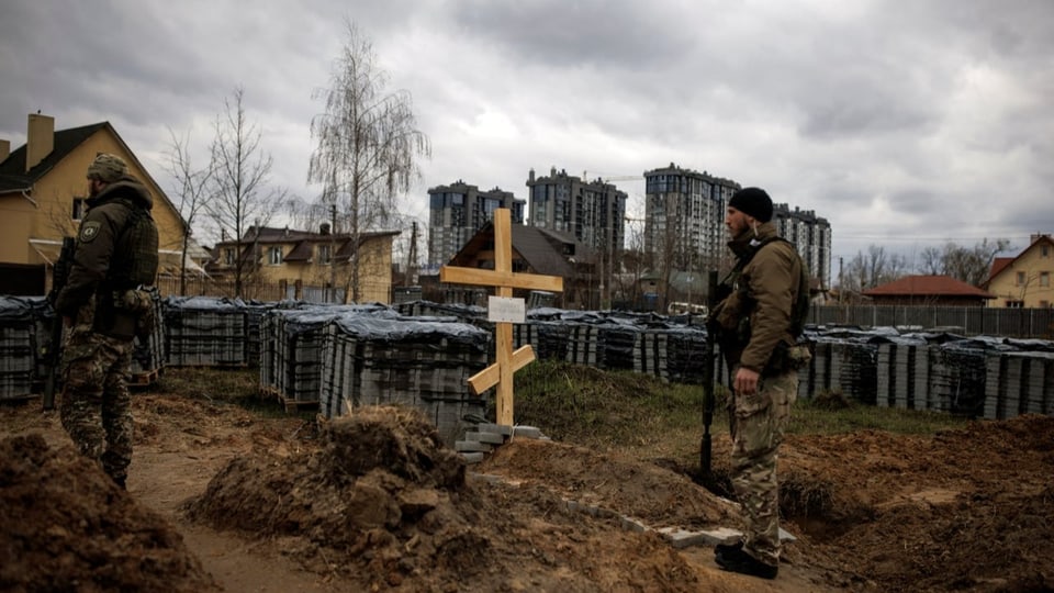 Ukrainische Soldaten vor einem Grab, in dem laut Anwohnern ein von Russen getöteter Bewohner Butschas liegt.