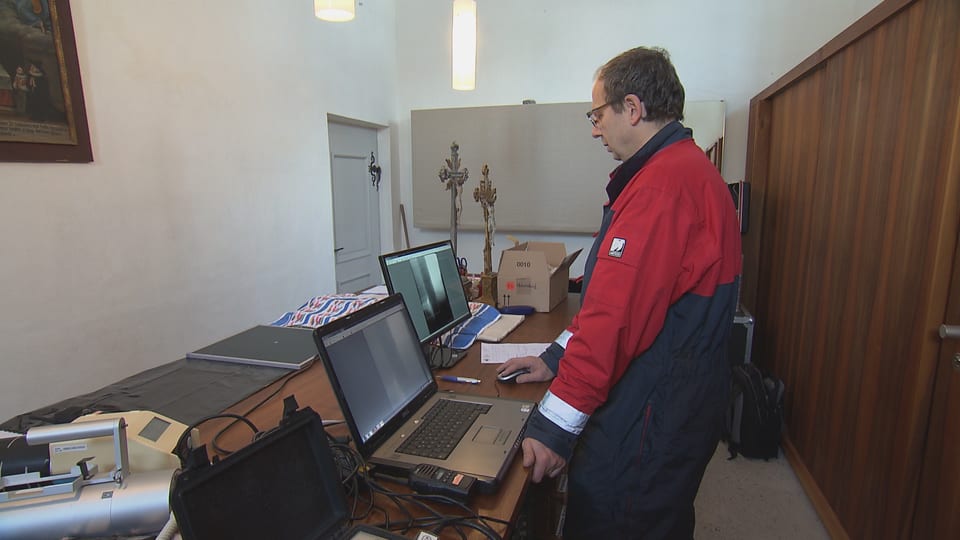 Ein Herr steht vor zwei Computern in der Sakristei.