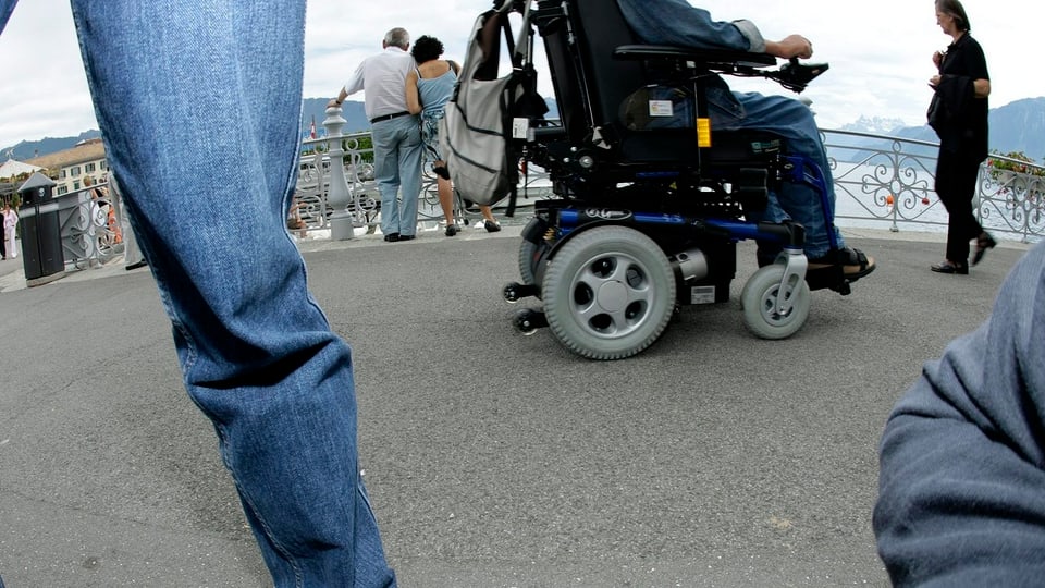 Ein Rollstuhlfahrer inmitten von Spaziergängern.