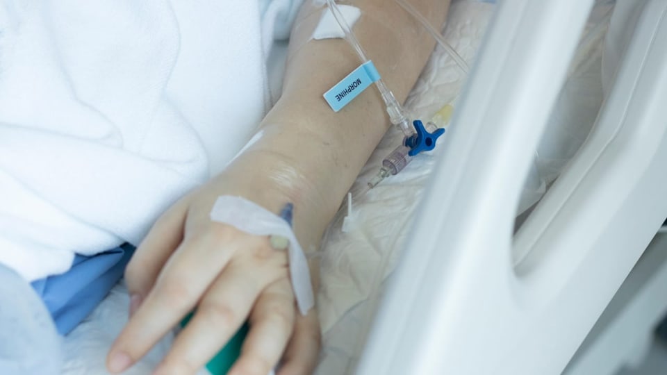 Einer Patientin im Spitalbett wird eine Morphin-Spritze gesetzt.
