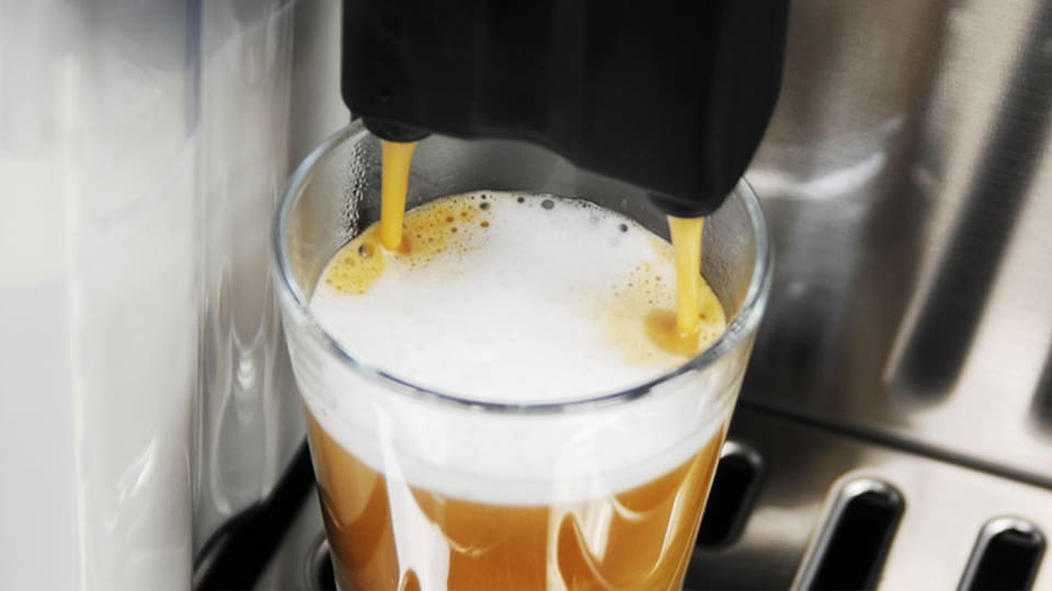 Kaffeevollautomat füllt ein Espresso-Macchiato in ein Espressoglas. 
