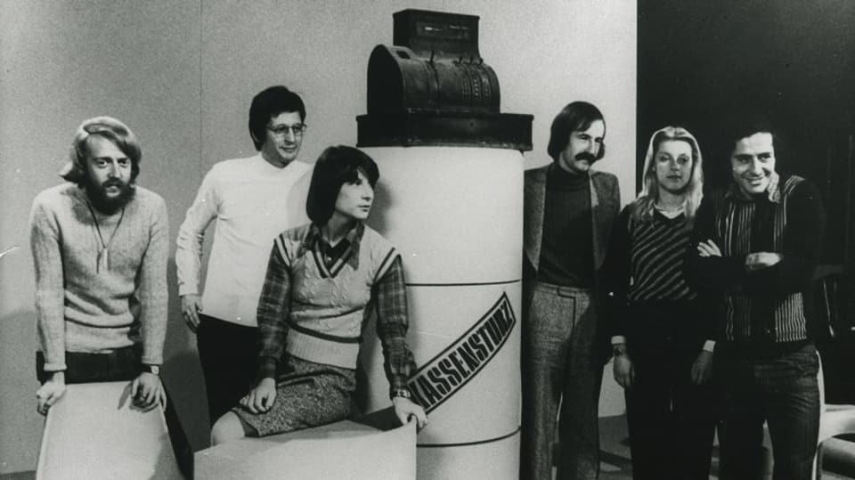 Redaktionsteam 1974 mit von links: Beat Regli, Walter Rüegg, Marianne Pletscher, André Francioli, Ruth Waldburger und Roger Schawinski, stehend um Studio-Kasse