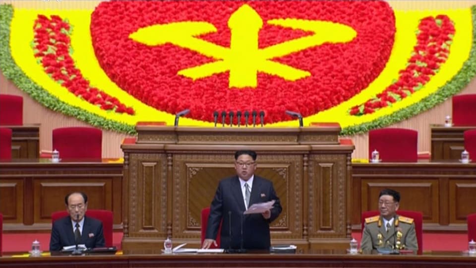 Kim Jong Un an einem Rednerpult hinter einem Emblem der Partei.