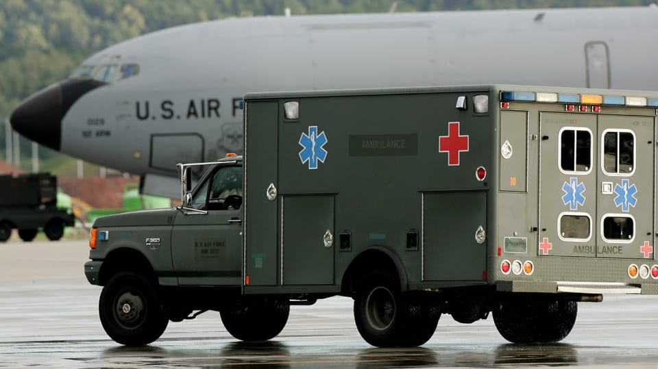Ein Krankenwagen, im Hintergrund eine US-Transportmaschine.