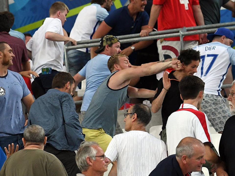 Ein russischer Fan schlägt einer anderen Person die Faust an den Hinterkopf.
