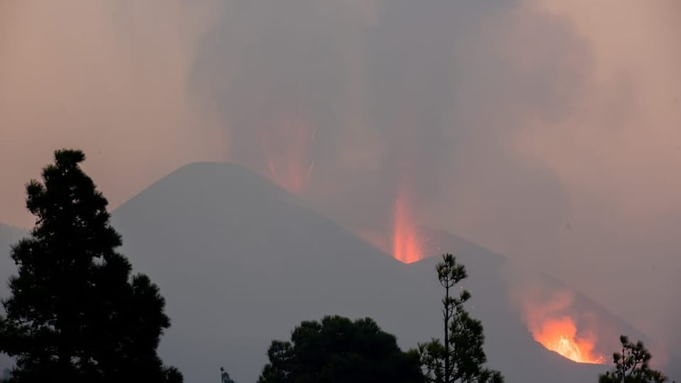 Der Himmel ist verdunkelt, aus dem Berg spritzt orangenfarbene Lava.