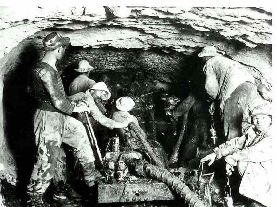 schwarz-weiss-Foto von Arbeitern in einem engen Stollen