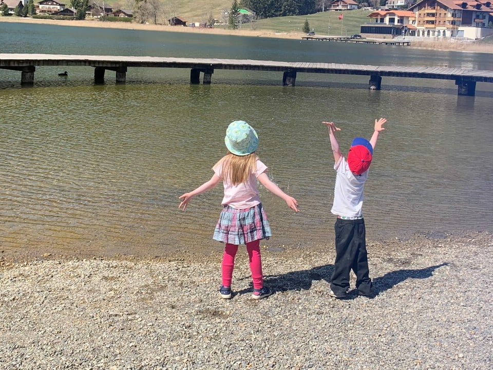 zwei Kinder spielen am See.