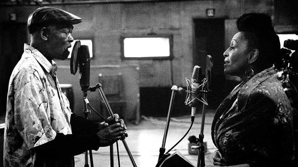 Schwarzweissbild: Ein Mann und eine Frau stehen sich in einem Tonstudio gegenüber und singen in Mikrofone