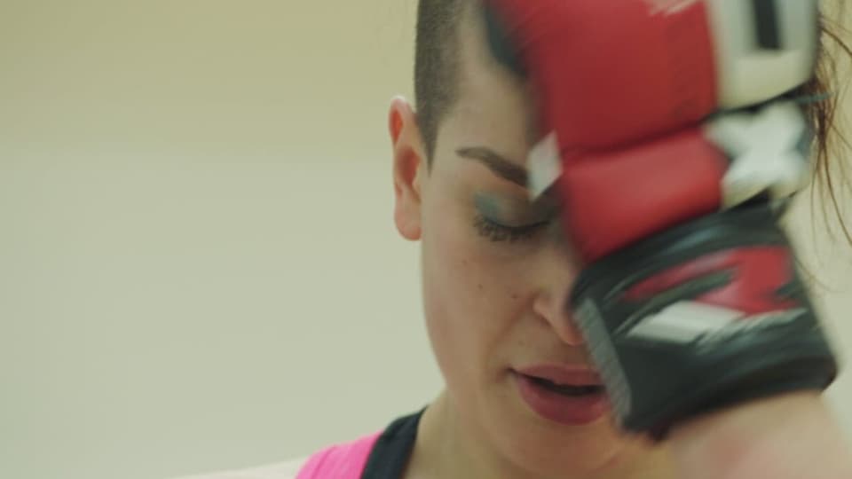 Junge Frau mit  Boxhandschuh vor dem Gesicht.