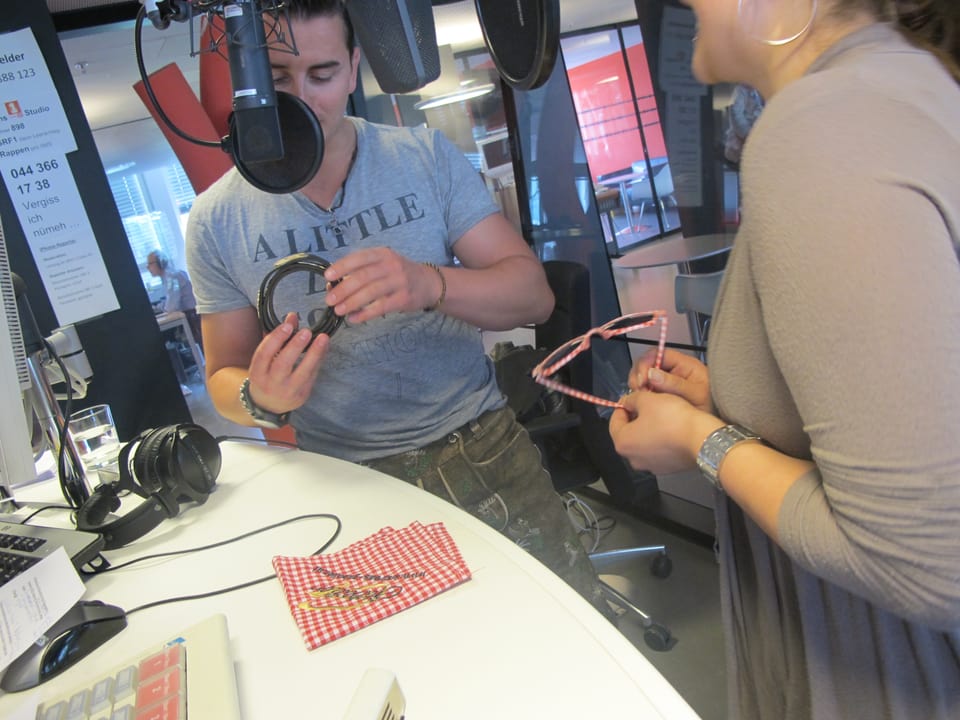 Im Studio von Radio SRF 1 überreicht Martina Gebistorf einen Gürten mit Kuhsujets an den österreichischen Sänger Andreas Gabalier im Tausch gegen eine Brille.