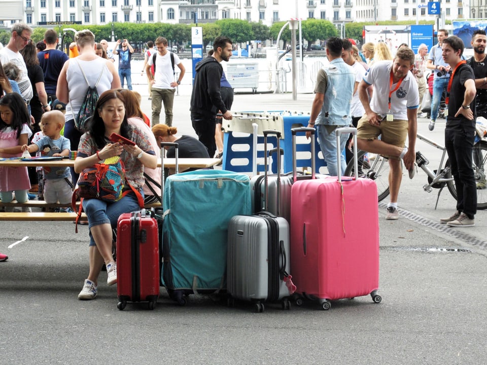 Eine Touristin sitzt mit ihren Koffern auf dem Europaplatz in der Stadt Luzern.