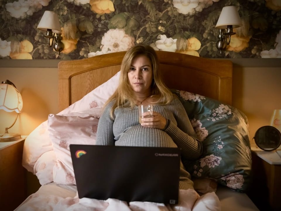Barbara Terpoorten als Anna-Maria Giovanoli liegt hochschwanger im Bett vor ihrem PC.