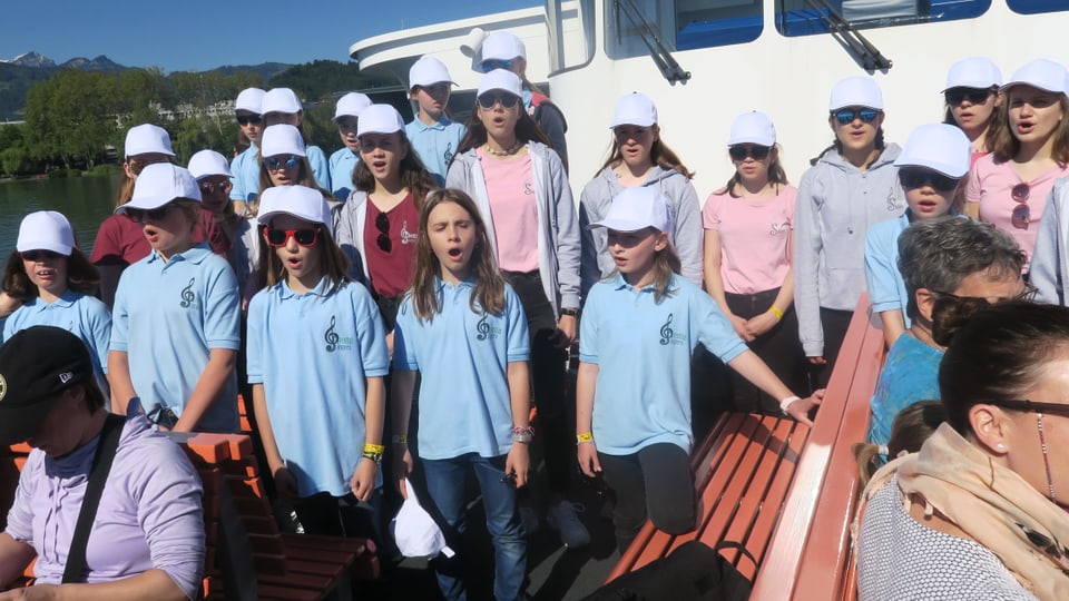 Kinder singen auf einem Schiff.