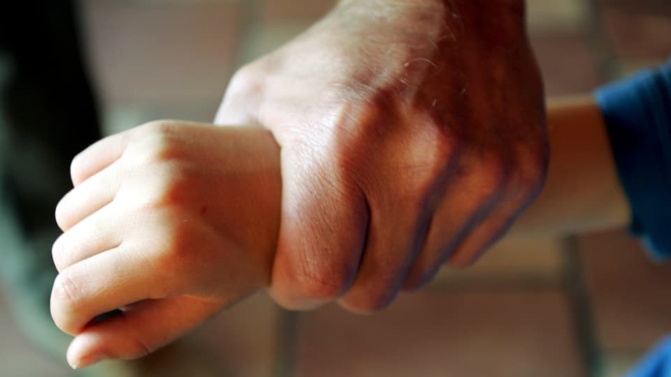 Männerhand umklammert Kinderhand.