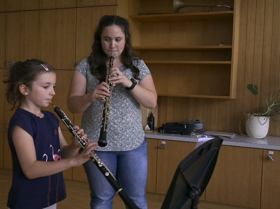 Musiklehrerin unterrichtet junges Mädchen, das Klarinette spielt, in einem Klassenzimmer.